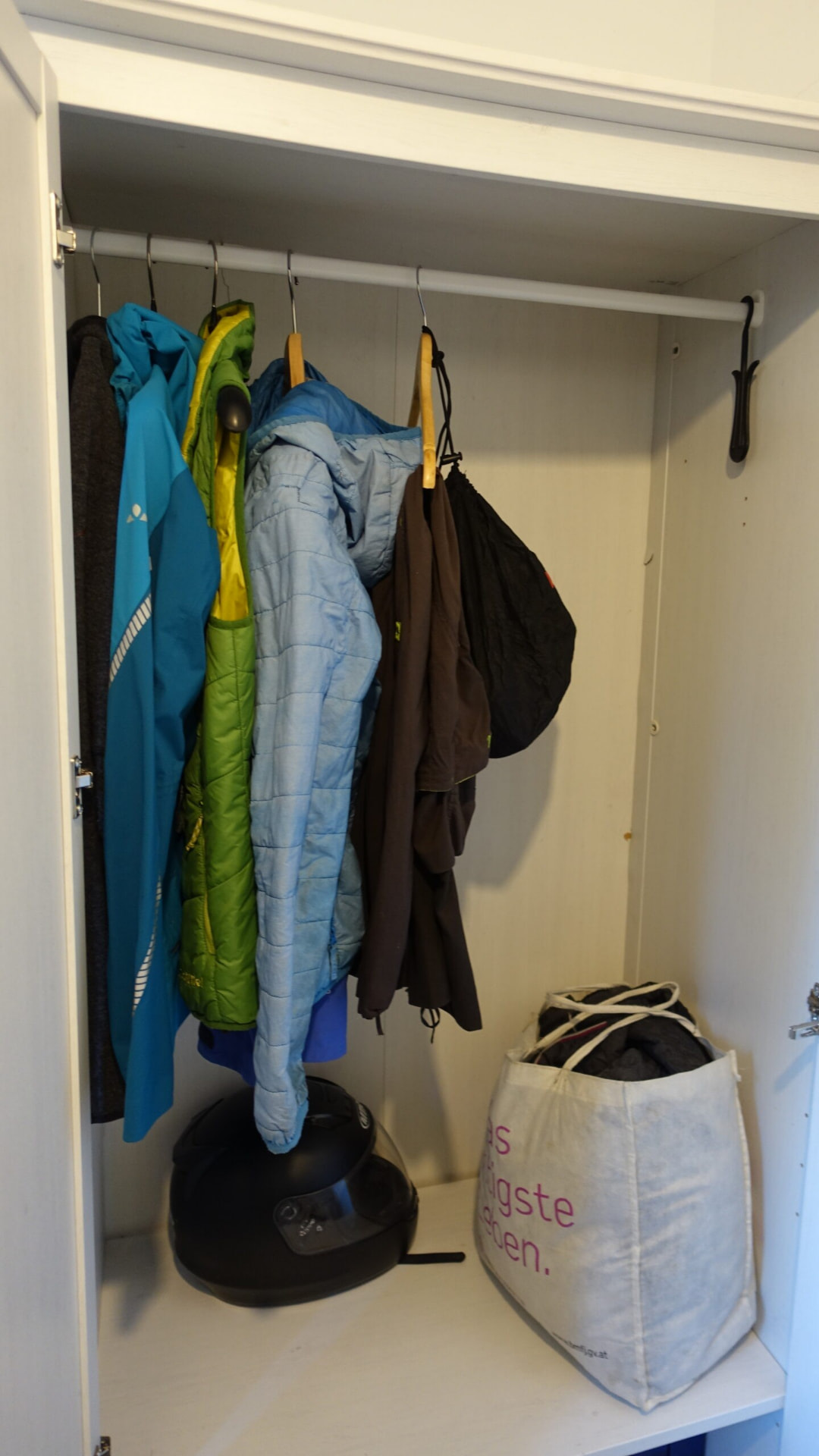 Aufgeräumter Kasten mit wenig Jacken und einem Motorradhelm