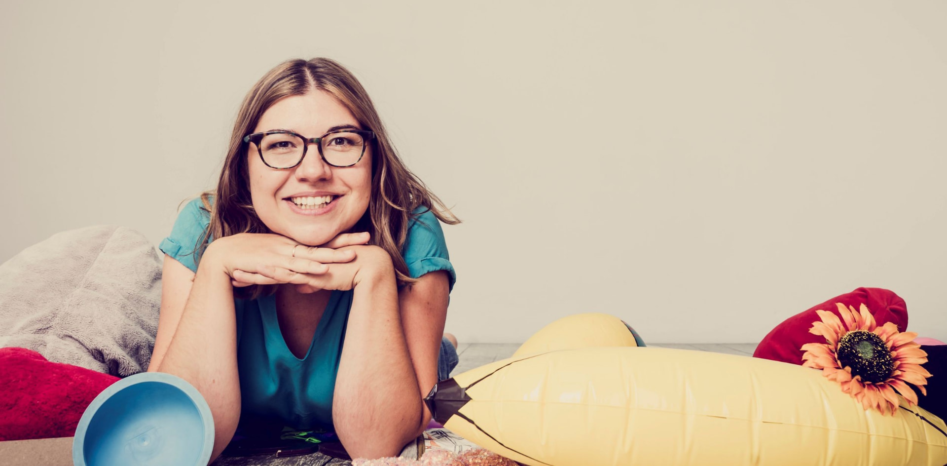 Anna liegt am Bauch inmitten von Zeug und lacht in die Kamera